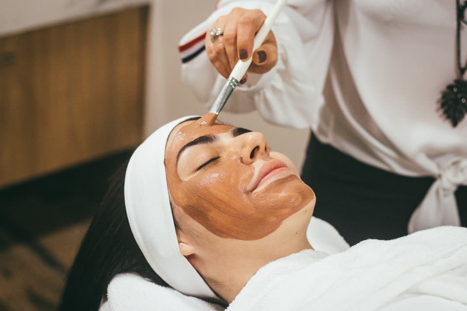 Professional applying a clay treatment mask to a client's face during a facial